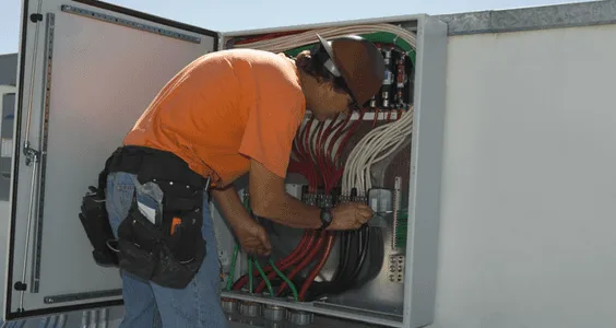 Electrician wiring the inside of a large electrical cabinet