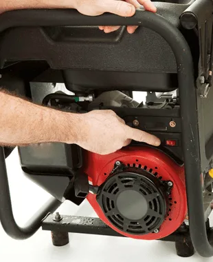 Hands carrying a portable generator by its frame