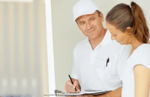 Electrician writing up an estimate on a clipboard with a homeowner
