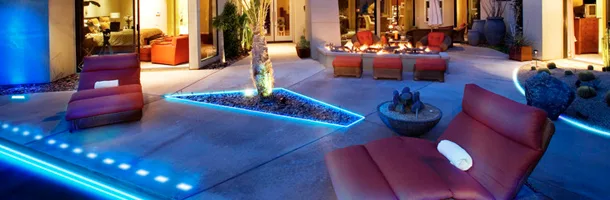 Outdoor patio lit at night with blue accent lighting around the seating area
