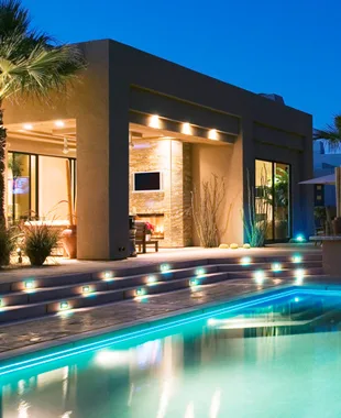 Modern home at dusk with a lit pool and illuminated steps