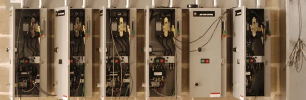 Row of open electrical panels with breakers and wiring
